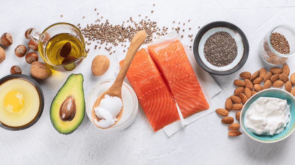 Assortment of healthy fats including salmon, avocado, nuts, and oils, emphasizing their crucial role in a balanced diet.