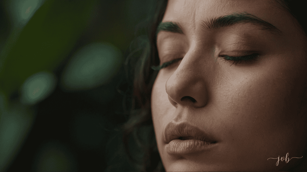 Close-up of a serene young woman with her eyes closed, surrounded by lush greenery, embodying a moment of deep self-awareness and introspection.