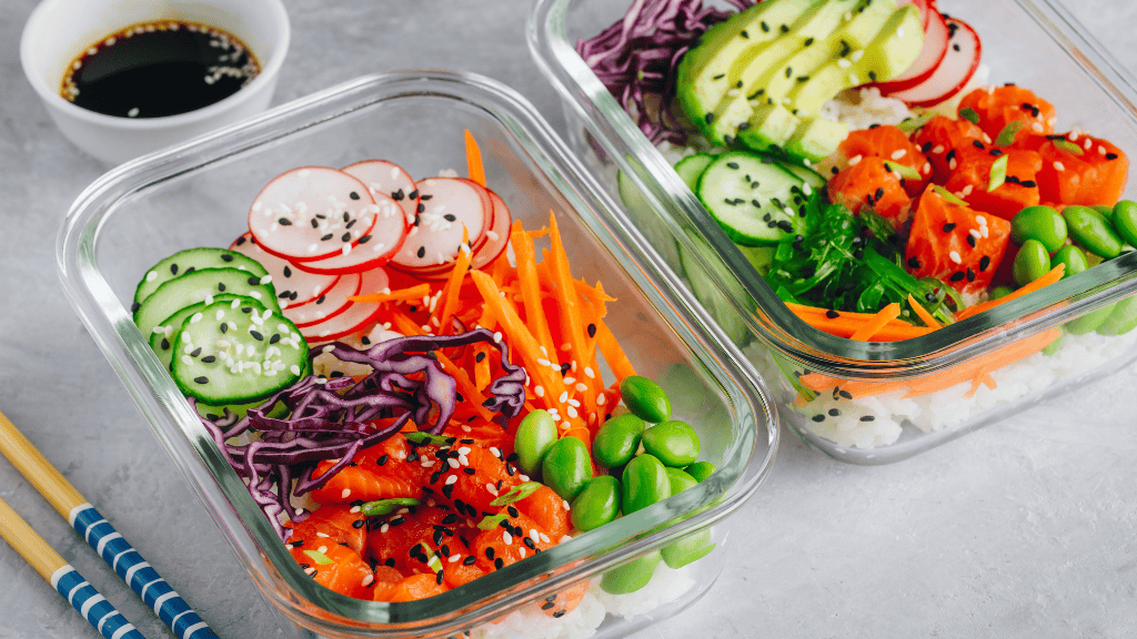 Two vibrant poke bowls with salmon, colorful vegetables, and rice in glass containers, perfect for a nutritious lunch.