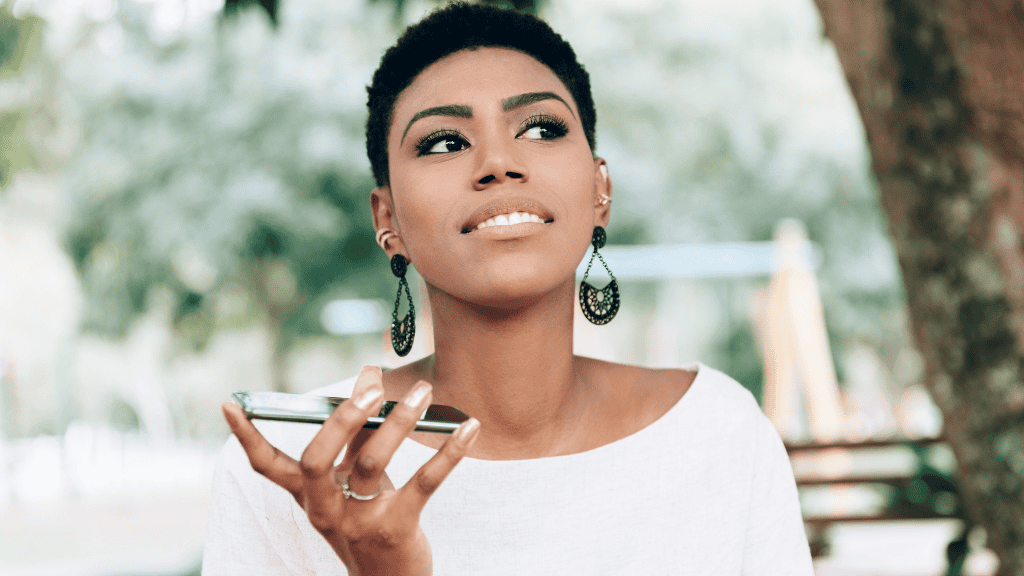 A confident African-American woman speaking on her smartphone in a park, looking upward with a thoughtful expression.