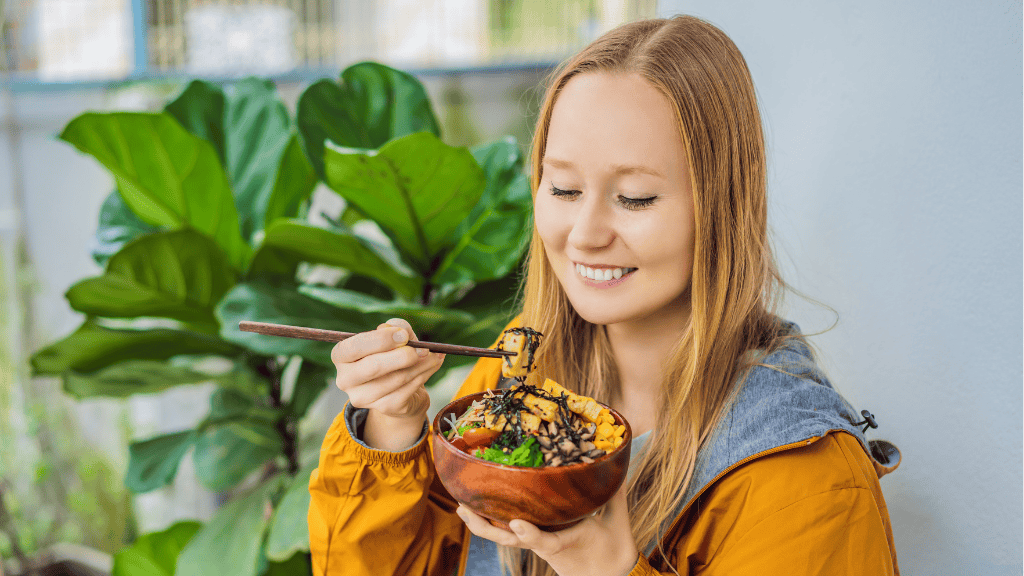 Happy young woman enjoying a bowl of healthy food, exemplifying the benefits of balanced nutrition.