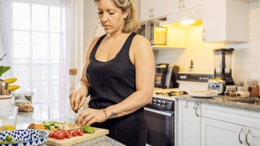 Woman preparing a healthy meal in her kitchen, chopping fresh vegetables to enhance her nutrition.