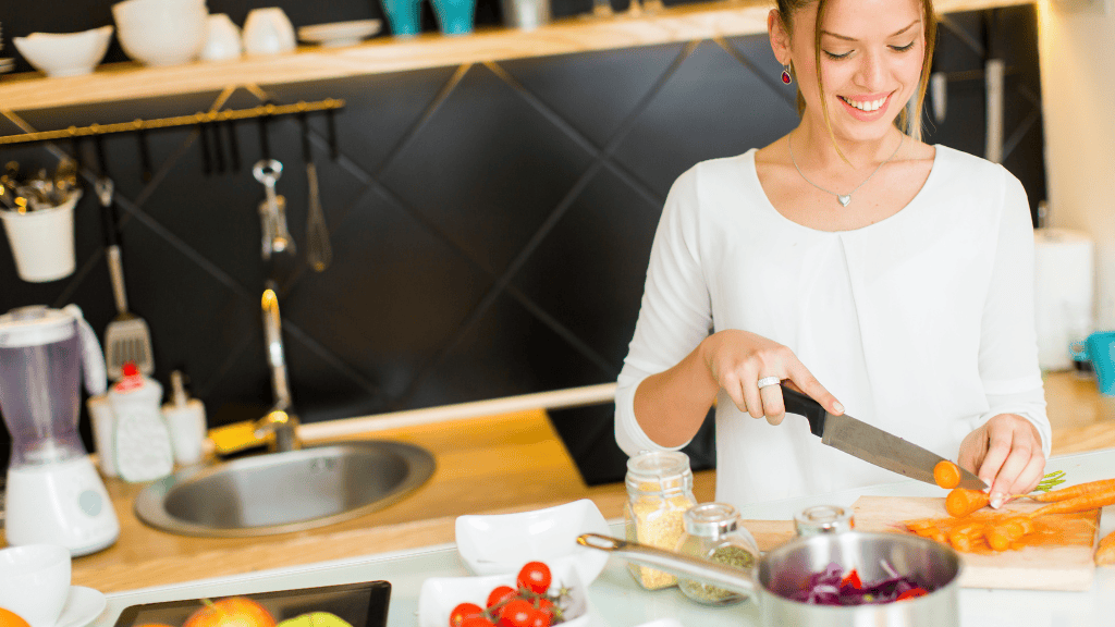 Smiling woman chopping fresh tomatoes in a modern kitchen, preparing meals for the week.