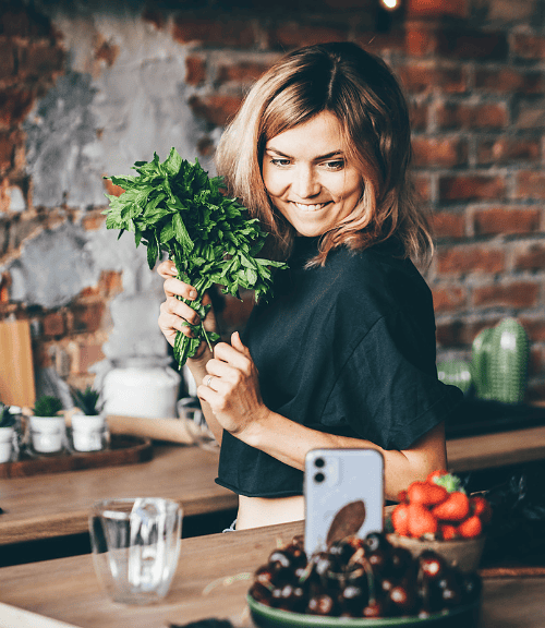 Woman joyfully holding fresh parsley in a rustic kitchen, embodying the spirit of meal planning with healthy, fresh ingredients.