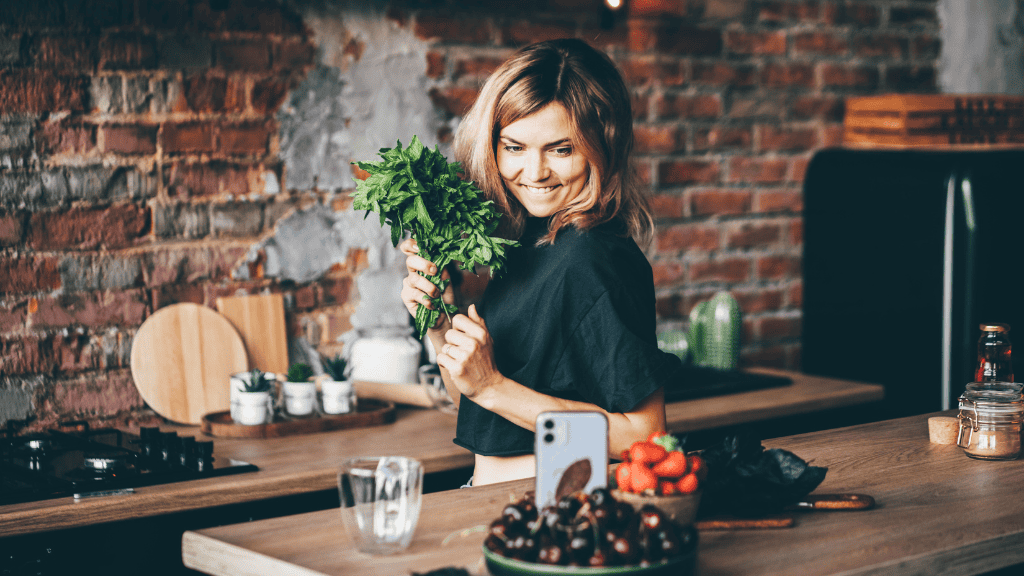 Woman joyfully holding fresh parsley in a rustic kitchen, embodying the spirit of meal planning with healthy, fresh ingredients.