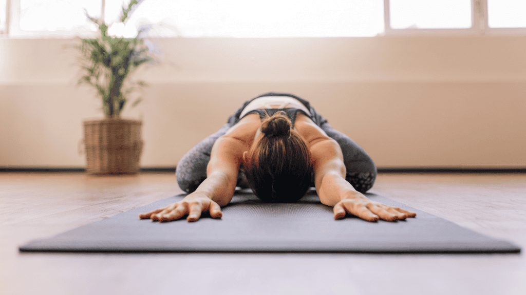 Text: Woman practicing deep yoga stretch on a mat