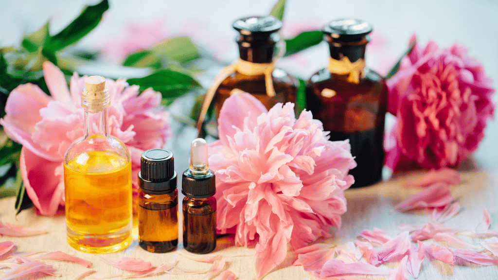 Vibrant essential oils and pink peonies on a wooden table