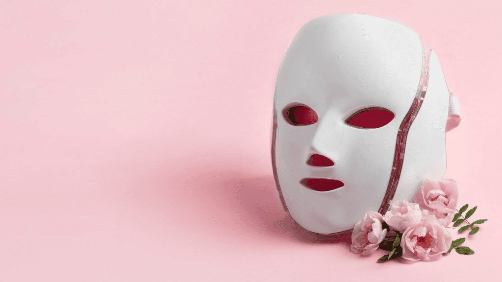 LED light therapy mask with pink roses on a soft pink background.