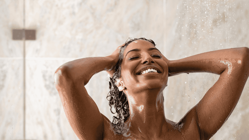 A woman enjoying a luxurious shower, smiling and relaxing under the water.