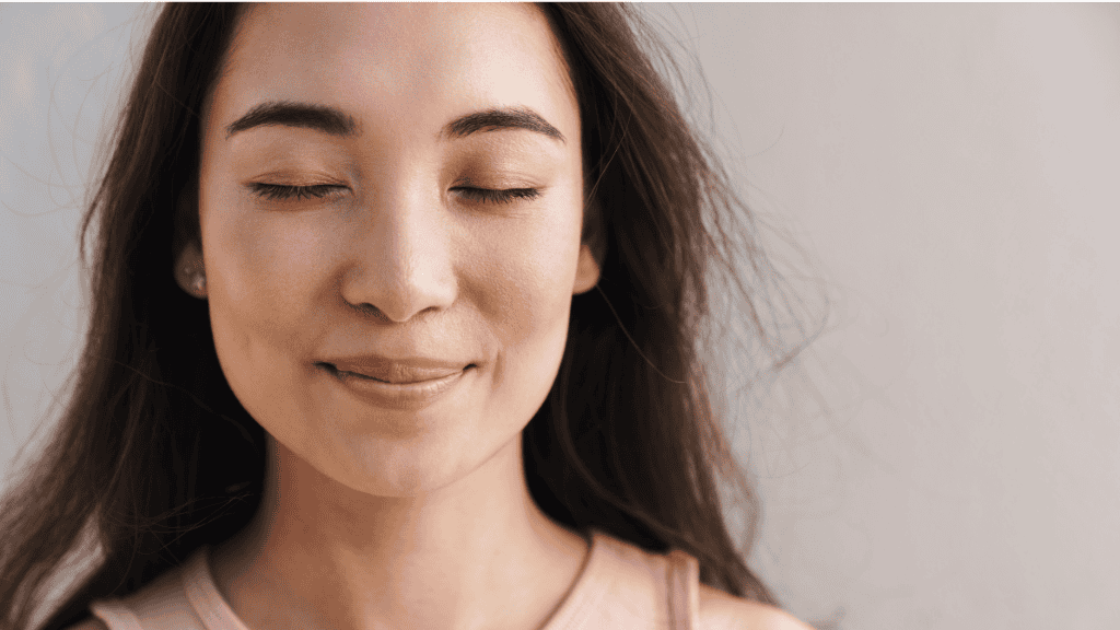 Close-up of a serene woman with closed eyes, smiling gently.