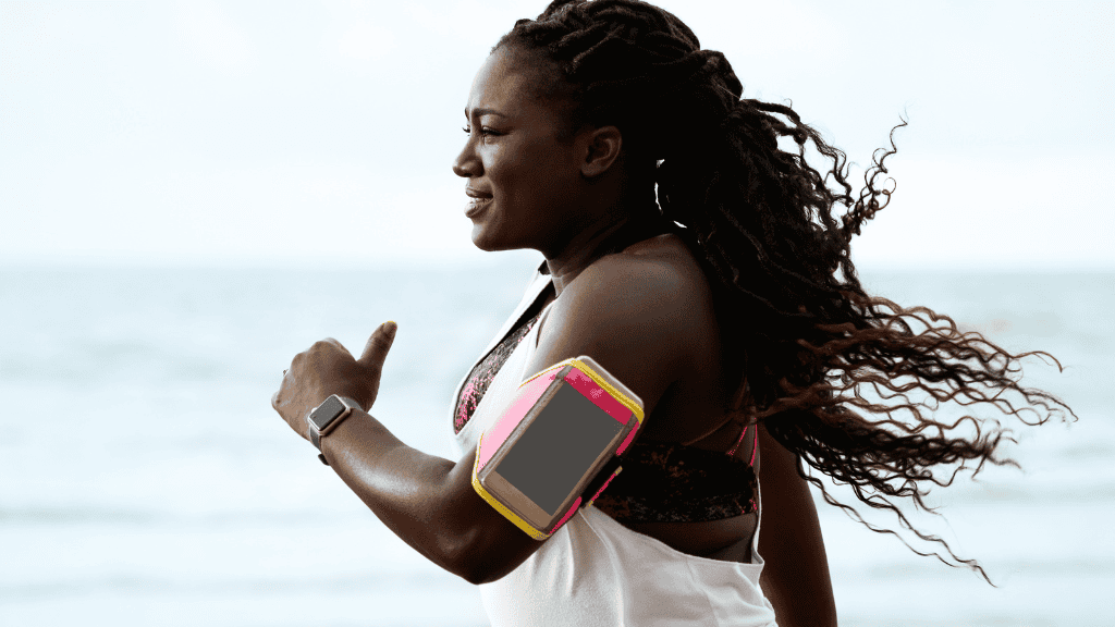 A woman with flowing dreadlocks jogging by the ocean, showcasing her commitment to a healthy body and wellness.