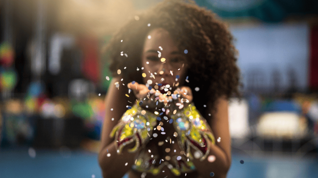 Young girl blowing colorful glitter confetti, celebrating with joy and excitement.