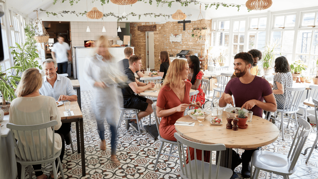 A diverse group of people enjoying a mindful meal together at a sunlit restaurant.