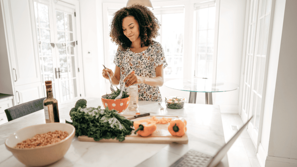 A woman preparing a healthy meal with fresh produce and whole grains in her kitchen.