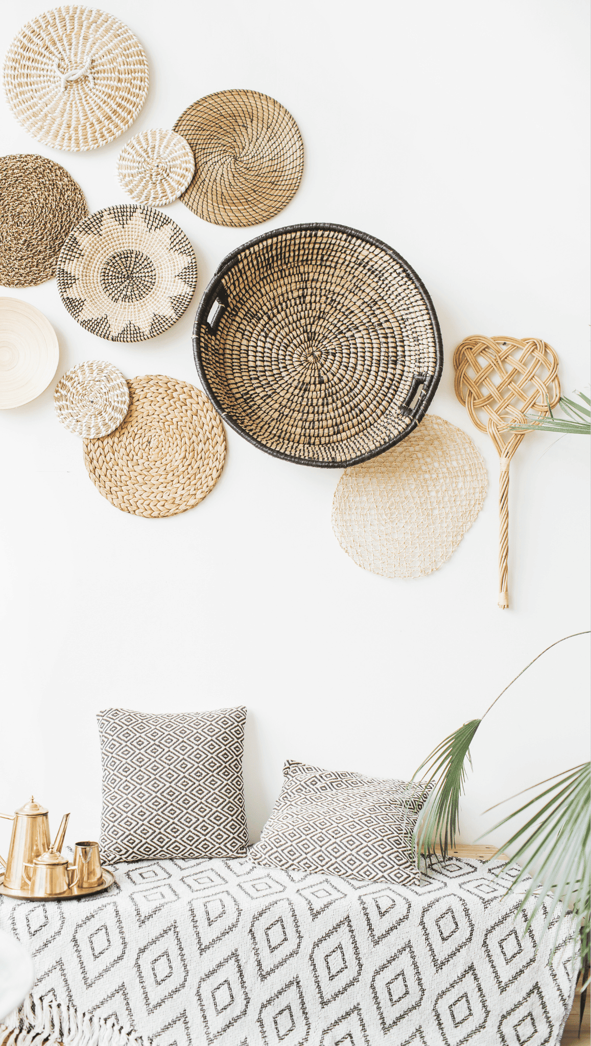 A modern, minimalist meditation space with black and white geometric textiles on a bench, woven baskets in various patterns on a white wall, and a leafy plant in the foreground.