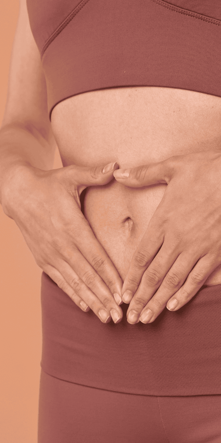 A person in mauve workout clothes forms a heart shape with their hands over their bare stomach, symbolizing a healthy lifestyle and Diet Plan, against a peach-colored background.